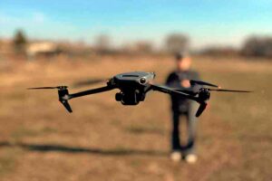 letnaya-praktika-dji-mavic-3-trenirovka Дрон DJI Mavic 3 в режиме зависания во время практического занятия. Девушка хочет стать пилотом дрона, она управляет дроном на открытой местности, отрабатывая навыки стабилизации и съёмки.